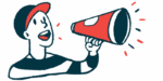 A person in a baseball cap speaks into a megaphone.