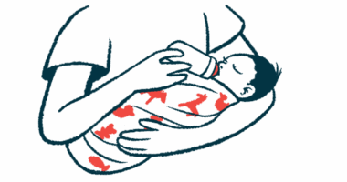 A baby cradled in a person's arms drinks from a bottle.